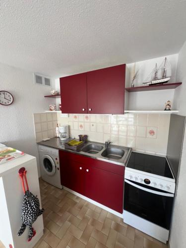une petite cuisine avec des armoires rouges et un évier dans l'établissement SABLES D'OR Joli T3 proche de la mer Plage Richelieu Cap d'Agde, au Cap d'Agde
