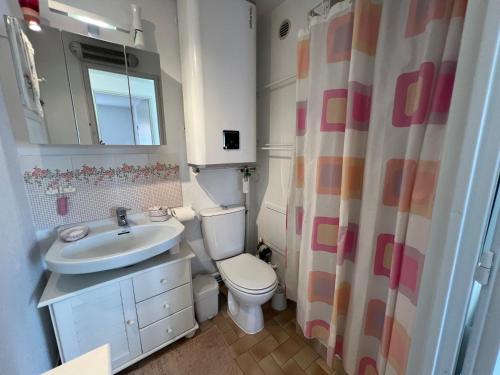 La salle de bains est pourvue d'un lavabo, de toilettes et d'un rideau de douche. dans l'établissement SABLES D'OR Joli T3 proche de la mer Plage Richelieu Cap d'Agde, au Cap d'Agde