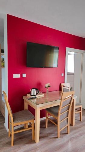 a dining room with a table and a red wall at Jaworina- Apartamenty, Domki i Pokoje in Solina