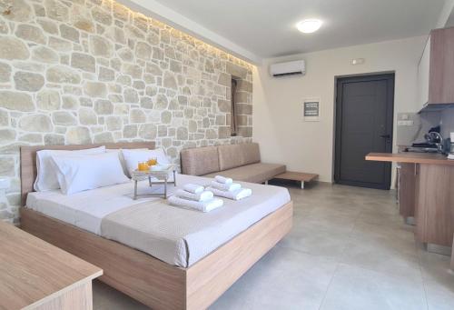 a bedroom with a bed and a stone wall at Studios Rosmari in Áyioi Pándes