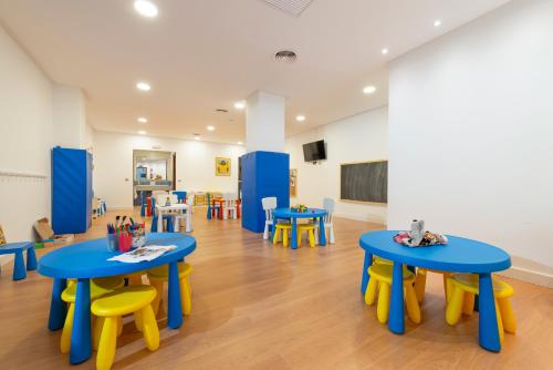 a classroom with blue and yellow tables and chairs at Can Picafort Palace in Can Picafort