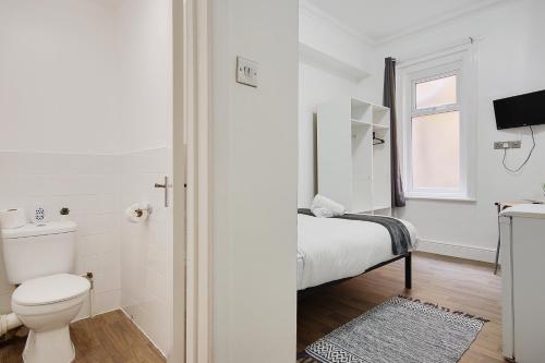 a white bathroom with a toilet and a sink at Bonnington Beach in Bournemouth