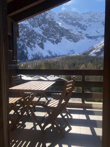 a wooden table and chairs on a balcony with a view at Joli logement pour 4 personnes à La Fouly in La Fouly