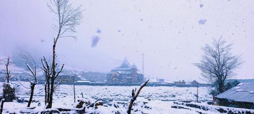 索纳马格Mitra Sonamarg的一座有雪盖的田野,后面有一座建筑