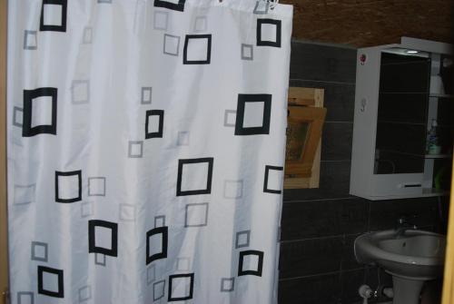 a bathroom with a white shower curtain with black squares at Brvnare Dunja 1 i Dunja 2 in Kraljevo