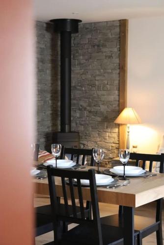 une table en bois avec des chaises et un poêle à bois dans l'établissement Gîte du Pré Chappa, Parc Naturel des Hautes Vosges, à Saint-Maurice-sur-Moselle