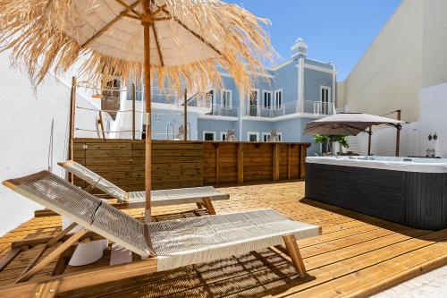 a patio with chairs and an umbrella on a deck at Dona Simone Boutique Suites & Studios - by @ rita's place in Faro
