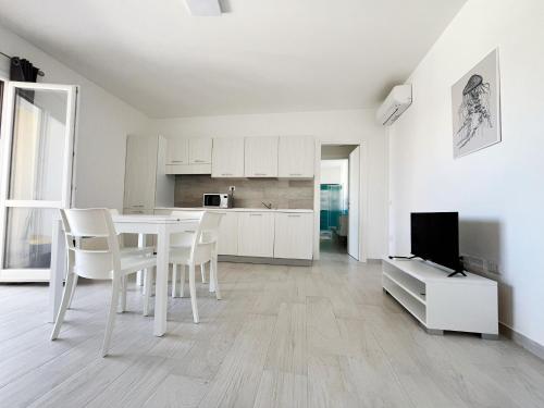 una cucina bianca con tavolo, sedie e TV di Affittimoderni La Maddalena - MADA22 a La Maddalena