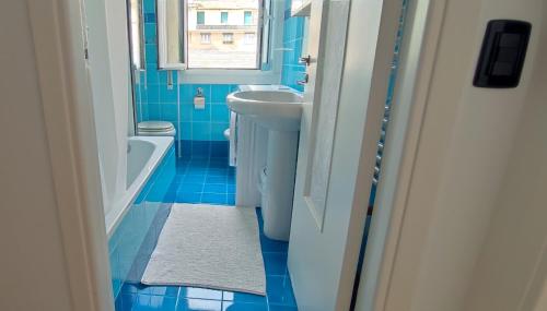La salle de bains bleue est pourvue d'un lavabo et d'une baignoire. dans l'établissement La terrazza sui tetti, à Gênes
