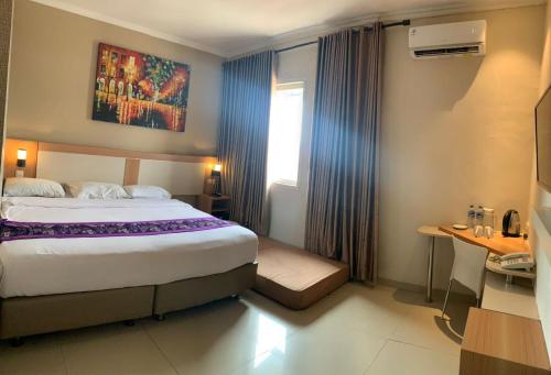 una camera d'albergo con un letto grande e una finestra di Laxston Hotel a Yogyakarta