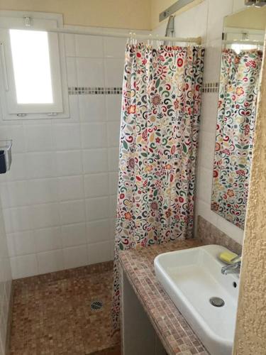 une salle de bain avec un rideau de douche et un lavabo dans l'établissement Appartement Marius, au Grau-du-Roi