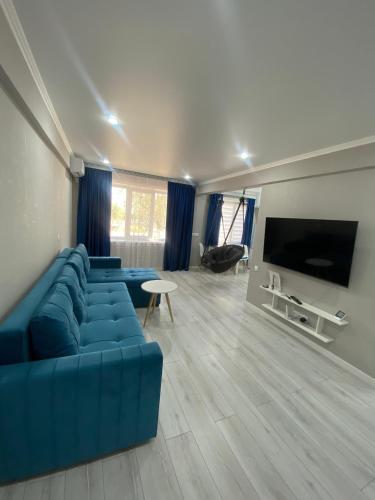 a living room with a blue couch and a flat screen tv at Двухкомнатная квартира-студия in Balqash