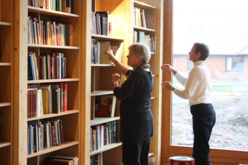 dwoje ludzi stojących w bibliotece patrzących na książki w obiekcie Løgumkloster Refugium w mieście Løgumkloster