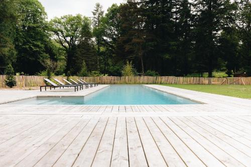einen Pool mit 2 Stühlen und eine Holzterrasse in der Unterkunft BANDIAT Le Domaine in Fargeas