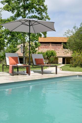 deux chaises et un parasol à côté d'une piscine dans l'établissement CHATEAU LAURIGA, à Thuir