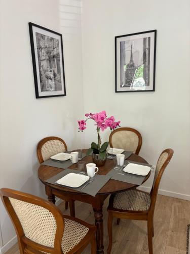 - une table à manger avec des chaises et des fleurs dans l'établissement Maison des Larris - proche Aéroport - navette Gare, à Beauvais