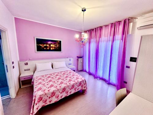 a bedroom with a bed with pink walls and windows at Ai Giardini Rooms -vicino Ospedale Borgo Trento e centro storico in Verona