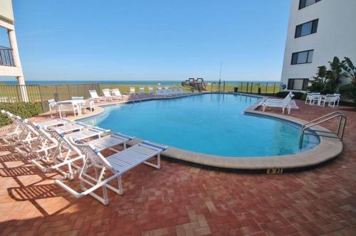 a swimming pool with chairs and tables and a building at Chadham by the Sea 413 in New Smyrna Beach