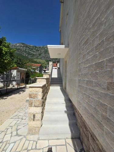 a stone wall next to a building with a sidewalk at Villa BOJANA AS Aparments Risan in Risan