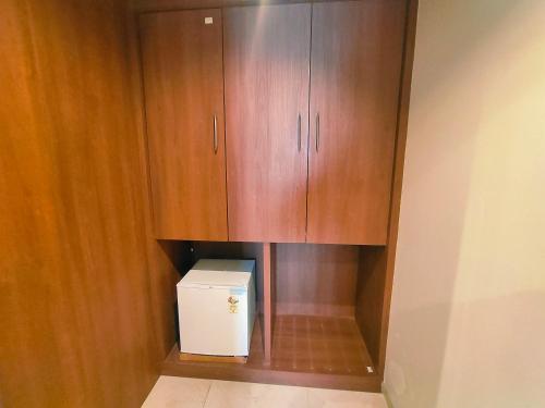 a small kitchen with wooden cabinets and a refrigerator at Hotel Kunal Palace in Ahmadnagar