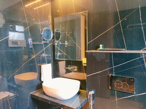 a bathroom with a toilet and a sink and a mirror at Hotel Kunal Palace in Ahmadnagar