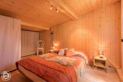 a bedroom with a bed in a room with wooden walls at Le Balcon de Novel - Chalet en pleine nature in Novel