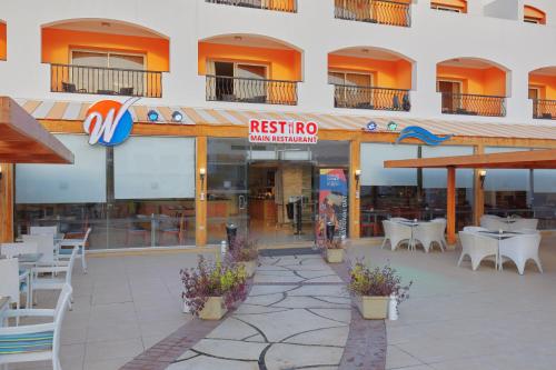 a restaurant with tables and chairs in front of a building at Fun & Sun Naama Waves in Sharm El Sheikh