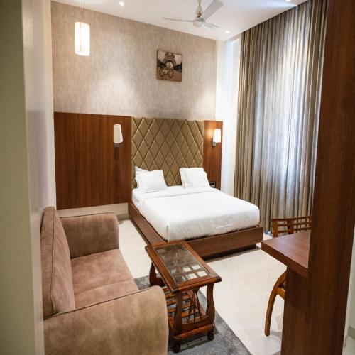 a hotel room with a bed and a chair and a table at Hotel Kunal Palace in Ahmadnagar
