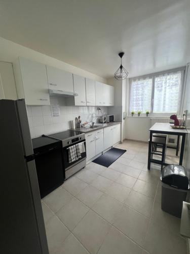 une cuisine avec des armoires blanches et une table à l'intérieur dans l'établissement Appt T3, 65 m2 proche de Paris, à Méry-sur-Oise