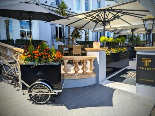 a flower cart parked next to a restaurant with umbrellas at Tynedale Hotel in Llandudno