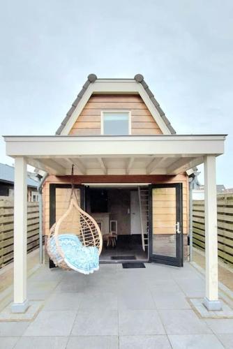 a house with a porch with a hammock on a patio at Have a nice stay! - Trendy Vakantiehuis Carpe Diem met eigen tuin in Noordwijk