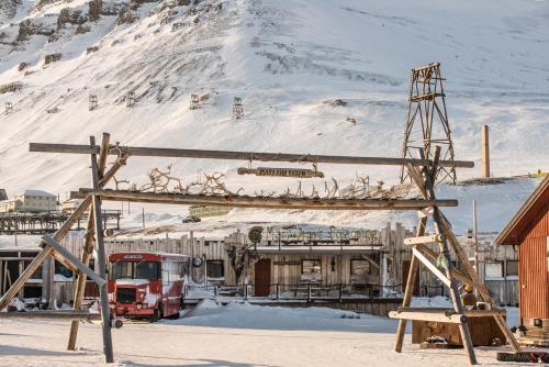 a train station in the snow with a snow covered mountain at Mary-Ann's Polarrigg in Longyearbyen