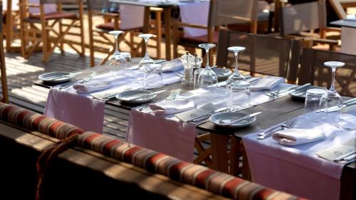 a table with plates and wine glasses on it at High Beach Resort in Malia