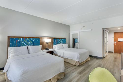 a hotel room with two beds and a chair at Hampton Inn Houston-Pearland, TX in Pearland