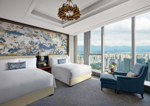 a bedroom with two beds and a chair and windows at Waldorf Astoria Chengdu in Chengdu