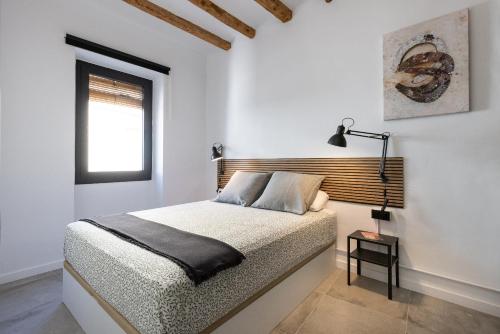 a white bedroom with a bed and a window at Alt Camp by Unik Vacation in Puigpelat