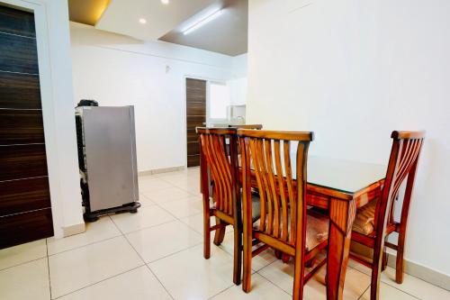 a kitchen with a table and chairs and a refrigerator at Elite Enclave - Mysore - 2BHK Luxury Serviced Apartments in Mysore