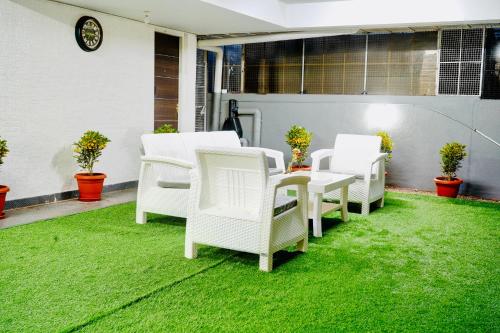 a group of white chairs sitting on a lawn at Elite Enclave - Mysore - 2BHK Luxury Serviced Apartments in Mysore