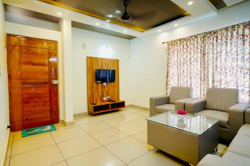 a living room with a couch and a tv at Elite Enclave - Mysore - 2BHK Luxury Serviced Apartments in Mysore