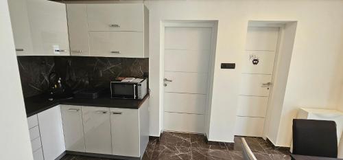 a kitchen with white cabinets and a microwave on a counter at ENA 1&2 -BIG FREE PRIVAT parking for BOATS, TRUCKs, combi,-CENTRAL HEATING !!! in Karlovac