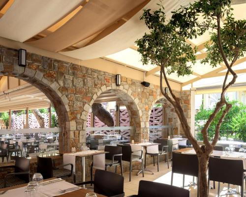 a restaurant with tables and chairs and a stone wall at High Beach Resort in Malia