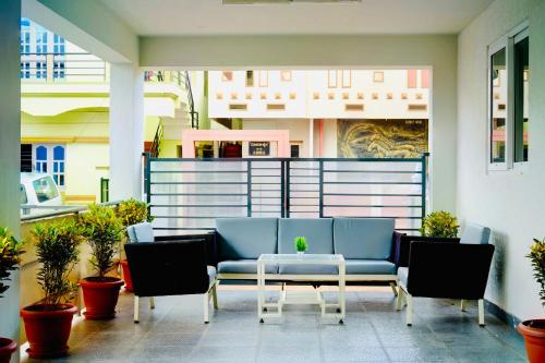 a patio with a blue couch and chairs and a table at Elite Enclave - Mysore - 2BHK Luxury Serviced Apartments in Mysore