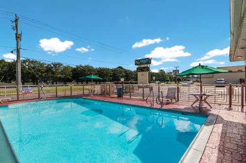a swimming pool with a picnic table and umbrella at Quality Inn Little Creek in Virginia Beach