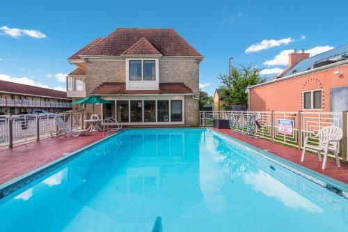 a swimming pool in front of a house at Quality Inn Little Creek in Virginia Beach