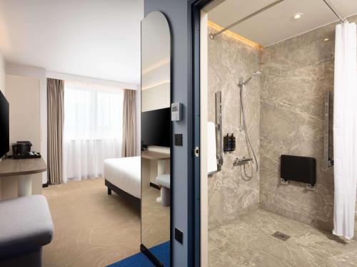 a hotel room with a shower and a bedroom at Mercure London Earls Court in London