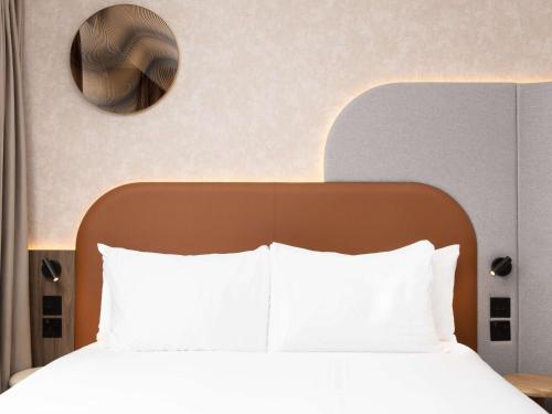 a bedroom with a bed with white sheets and a mirror at Mercure London Earls Court in London
