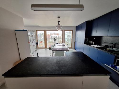 une cuisine avec des armoires bleues et un comptoir noir dans l'établissement Appartement lumineux et moderne à Boulogne, à Boulogne-Billancourt