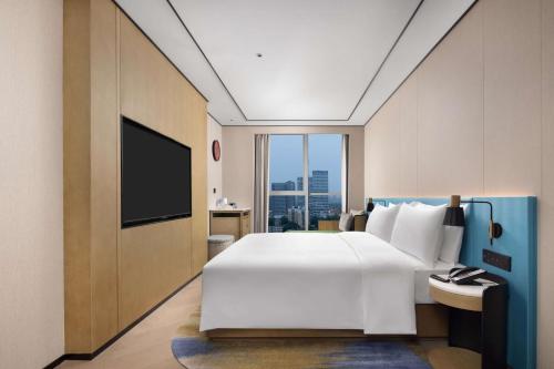 a bedroom with a large white bed and a large window at Hilton Garden Inn Chengdu Chenghua in Chengdu