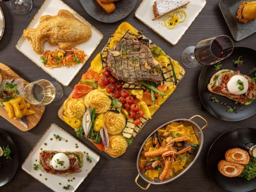 a table topped with plates of food and glasses of wine at Mercure London Earls Court in London