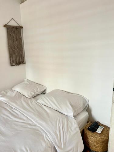 a white bed with two pillows and a basket next to it at Melambai in Eilat